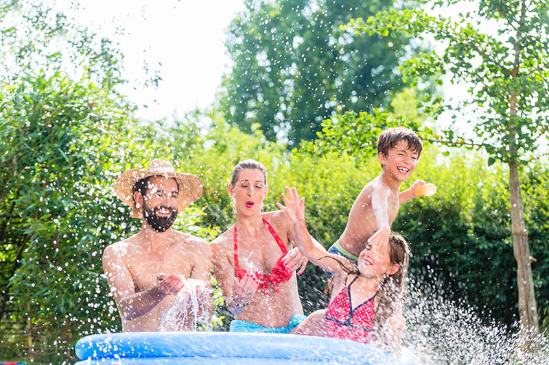 Family cooling down splashing water in garden pool